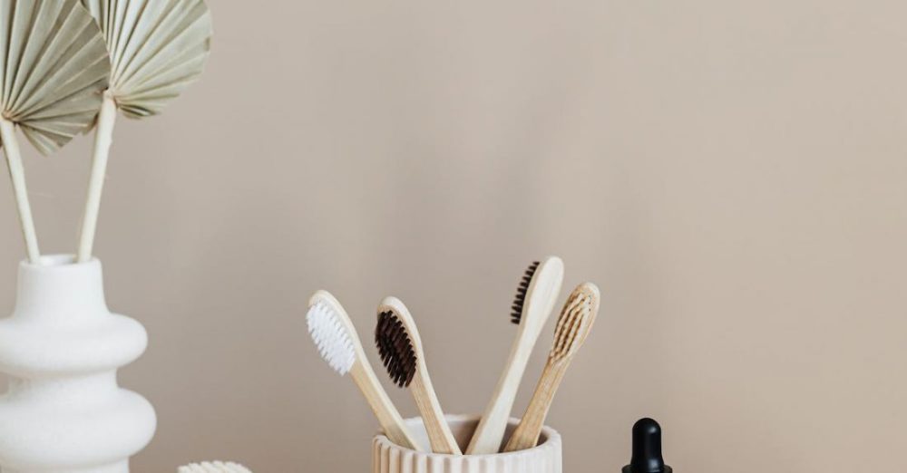Dental Issues - Collection of bamboo toothbrushes and organic natural soaps with wooden body brush arranged with recyclable glass bottle with natural oil and ceramic vase with artificial plant